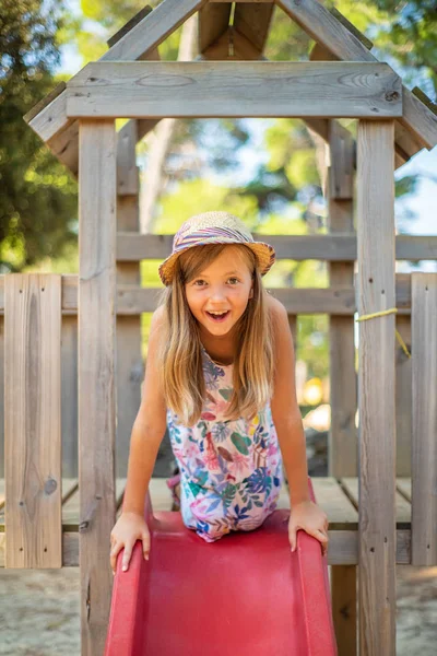 Menina Loira Bonito Com Chapéu Sentado Slide Parque Infantil — Fotografia de Stock