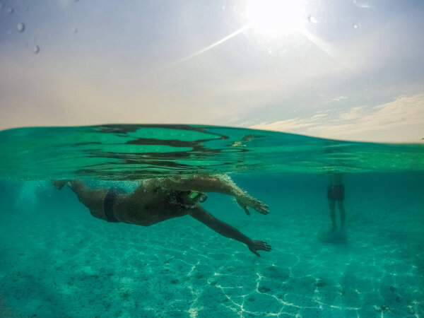Underwater split screen view of man diving apnea.