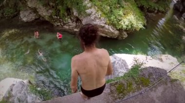 Ağır çekim uzun saçlı adamın rock nehir Soca Valley, Slovenya içine atlama.