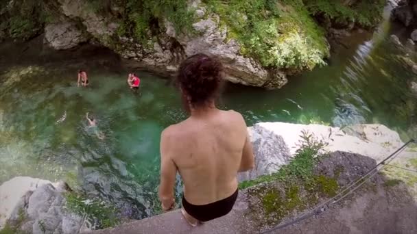 Zeitlupe eines langhaarigen Mannes, der im slowenischen Soca-Tal vom Felsen in den Fluss springt.