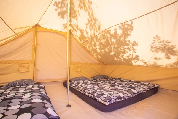 Tent interior with mattresses and grey duvet covers.