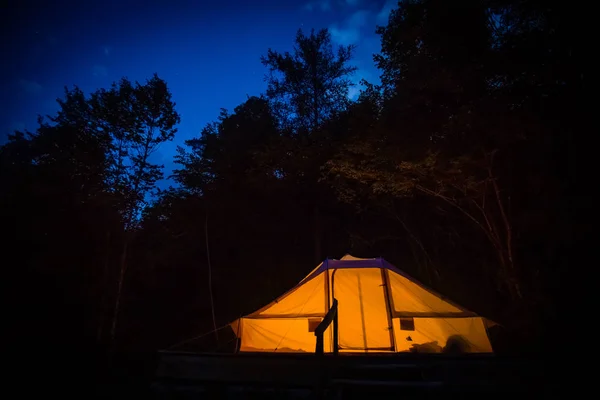 Illuminated family tent at night in Adrenaline Check eco resort in Slovenia.