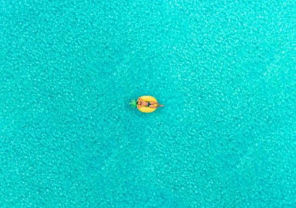 在透明的海面上漂浮在充气菠萝形床垫上的人的鸟图 — 图库照片