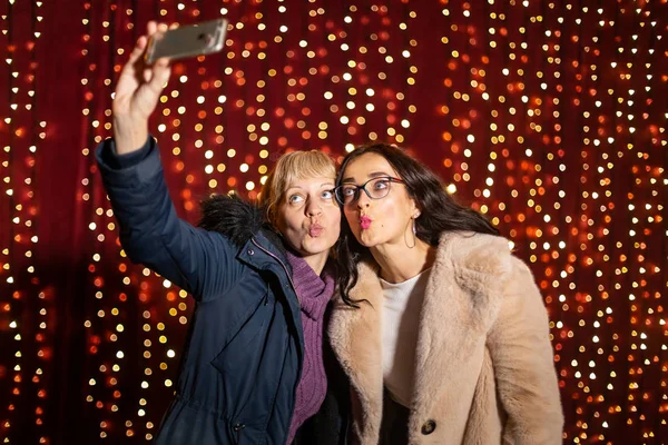 Duas Mulheres Atraentes Tirando Selfie Frente Parede Luz Mercado Natal — Fotografia de Stock