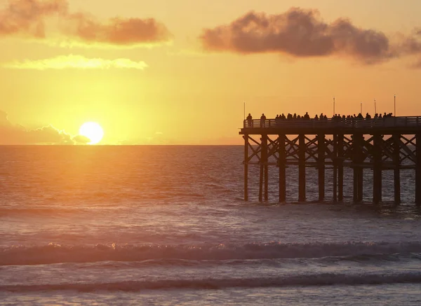 Een menigte op een Pier horloges de ondergaande zon — Stockfoto