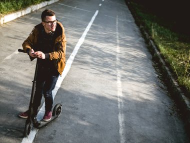 Kickscooter 'daki genç adam akıllı telefonlu.