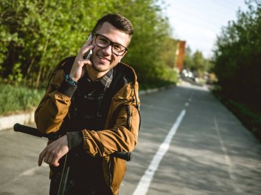 Kickscooter 'daki genç adam akıllı telefonlu.