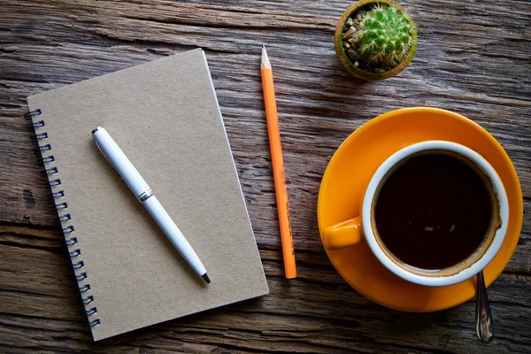Kahve fincanı sıcak ve dizüstü defter kalem ahşap masa masa üzerinde