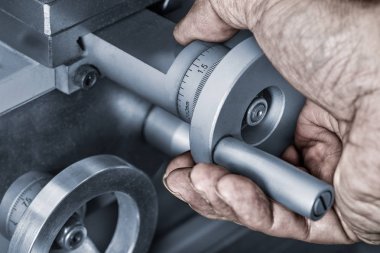 Bir makine araç üzerinde beslenme kontrol tekerleklerin yakın çekim. Doğru ölçmek için bir vernier ölçekli metal düğme üzerinde kirli bir el detayını. Endüstriyel üretimde hassas çalışma fikri.