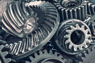 Close-up of various steel gear wheels. Cogged parts in duplex toning. Abstract technical background from the pile of metallic cogwheels. Idea of quality, engineering industry and technology. clipart
