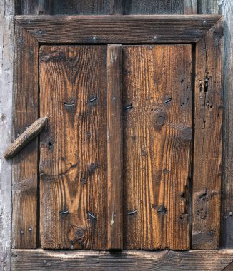 Ahşap rustik küçük kapı tarafından döner bir kilidi kapalı. Çivi ve deniz mili ile kahverengi kabaca dokulu ahşap küçük kırsal kapıdan. Köy arka planını vintage plakalar, çerçeve çıtaları ve emniyet kilidi.