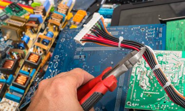Elektronik atık bertarafı. El pense ile. Bilgisayar anakart güç kabloları konektörle. Devre kartlarına, demonte floresan lamba Başlatıcı ve bilgisayar parçaları bulanık renkli arka plan üzerinde.