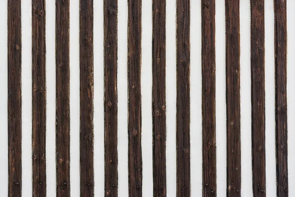 Contrasting striped texture with decorative wood battens. White painted wall with vertical stripes of old brown knotted planks. Original wooden background. Idea a renovation, housing design, architecture.