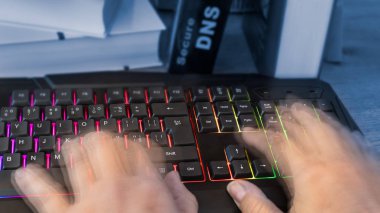 Renkli bilgisayar klavye hareket insan eliyle. Hacker, casus veya sansür parmak yazarak yakın çekim. Ayrıntılı arka plan güvenli Dns yazılar olan bir kitap. Sayısallaştırma ve siber güvenlik fikri.