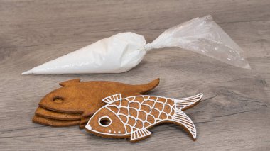 Noel pasta ve buzlanma çanta ahşap arka plan üzerinde yığılmış. Geleneksel Xmas nad, yakın çekim yeni yıl gingerbreads balık şeklinde. Şeker Tepesi ile aromatik bir tatlı çerezleri dekorasyon için hazırlık.