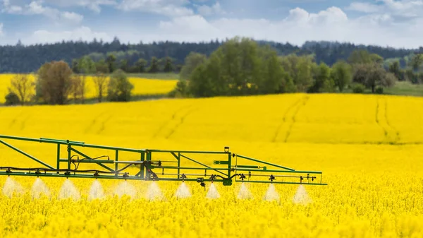 Detalhe do pulverizador agrícola. Campo de colza florido. Brassica napus — Fotografia de Stock