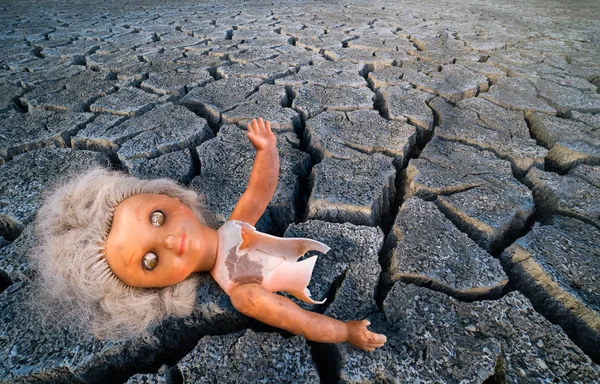 Muñeca de plástico vieja abstracta sobre fondo seco de tierra quemada — Foto de Stock