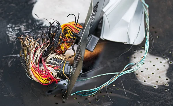 Trafik veya endüstriyel kazadan dolayı yanmış enkazların yakınına. Renkli elektrik kabloları yangından zarar gördü. Konsolu kapat. Kırık alüminyum profil ve yanmış metal levha. Hava, araba veya tren kazası..