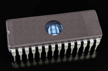 Silinebilen programlanabilir okunabilir bellek. Siyah arkaplanda EPROM çipi. Dijital entegre devre, ultraviyole ışıkla veri silmek için şeffaf pencereli DIP paketinde ince gümüş kablolarla ölür.