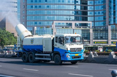 Xiamen, Çin - 30 Mayıs 2018: Sis topçu sanitasyon iş kamyon Modern binanın arka plan ile yolda