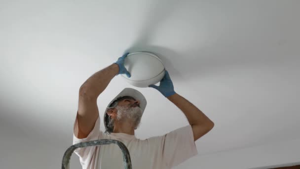 Man Die Een Lamp Aan Het Plafond Installeert — Stockvideo