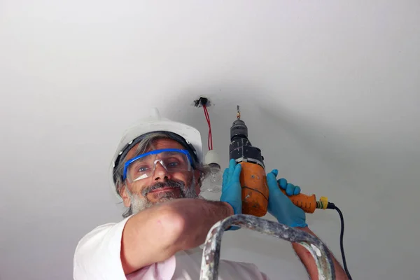 Elektrikli Matkapla Gülümseyen Adam Tavana Bir Lamba Yerleştiriyor — Stok fotoğraf