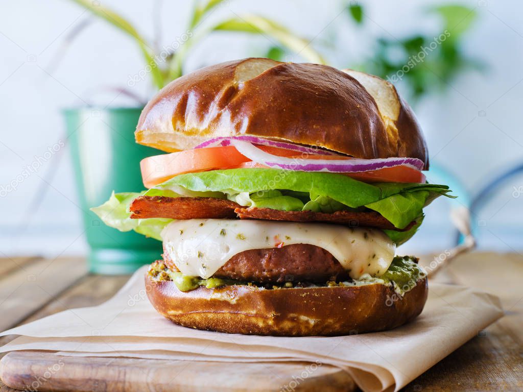 vegan cheese burger on pretzal bun and meatless bacon