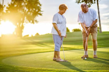 aktif kıdemli yaşam tarzı, gün batımında birlikte golf oynarken yaşlı çift