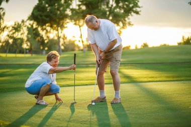 aktif kıdemli yaşam tarzı, gün batımında birlikte golf oynarken yaşlı çift