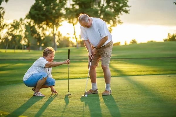 active senior lifestyle, elderly couple playing golf together at sunset