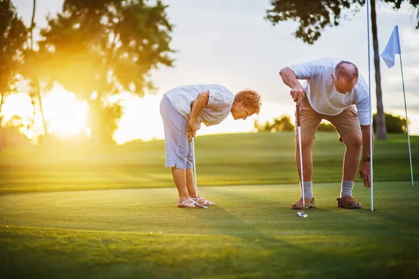 aktif kıdemli yaşam tarzı, gün batımında birlikte golf oynarken yaşlı çift