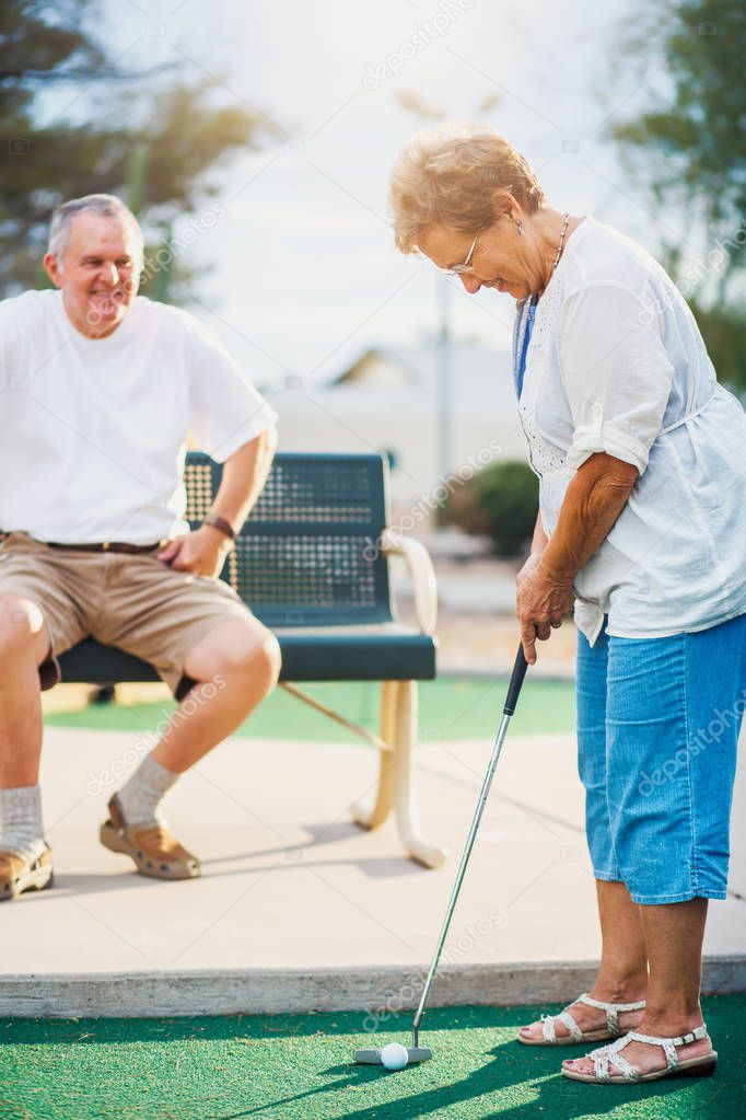 active elderly senior couple playing miniature golf together