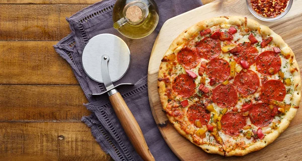 Pizza al salame su vassoio di servizio in legno con taglierina flat lay comp — Foto Stock