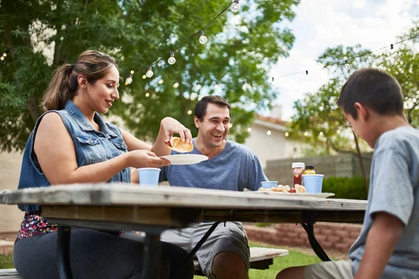 Happy Hispanic Family Eating Grilled Hot Dogs Picnic Table Backyard — Stock Photo, Image