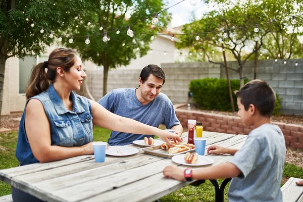 Happy Hispanic Family Eating Grilled Hot Dogs Picnic Table Backyard — Stock Photo, Image