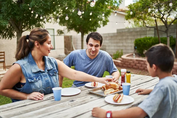 Happy Hispanic Family Eating Grilled Hot Dogs Picnic Table Backyard — Stock Photo, Image