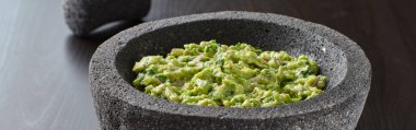 fresh guacamole in stone molajete panoramic composition clipart