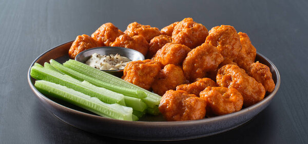 plate of boneless chicken wings with buffalo sauce and celery sticks