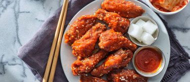 Gochujang soslu Kore usulü kızarmış tavuk kanadı, turp turşusu ve geniş kimchi karışımı.