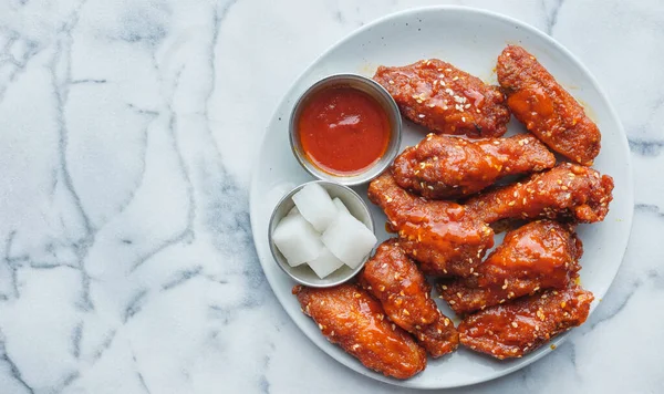 korean fried chicken wings in gochujang sauce with pickled radish and kimchi