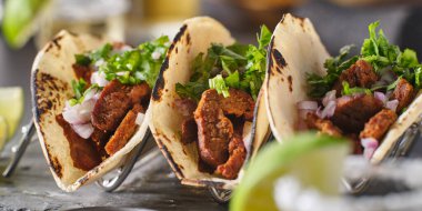 Üç Meksika carne asada sokak tacosuyla metal taco tutacağı.