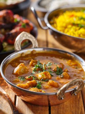 Hindistan tereyağlı tavuk körili balti tabağı masanın üstünde.