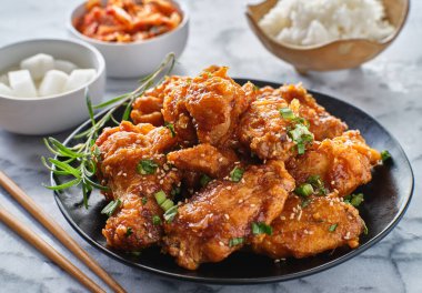 Galbi soslu Kore usulü kızarmış tavuk kanadı turp, kimçi ve pilav tabağı.