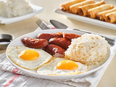 Filipino Silog kahvaltısı, sarımsaklı pilav, longsilog, ve iki güneşli yumurta.