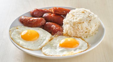 Filipino Silog kahvaltısı, sarımsaklı pilav, longsilog, ve iki güneşli yumurta.