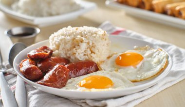 Filipino Silog kahvaltısı, sarımsaklı pilav, longsilog, ve iki güneşli yumurta.