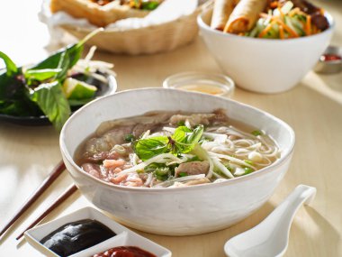 Vietnam yemeği ve sığır eti pho bo çorbası yanında da hoisin sosu ve sriracha.
