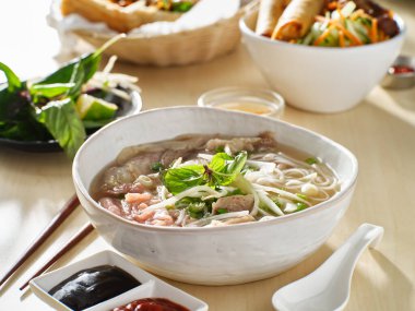vietnamamese meal with beef pho bo soup accompanied by hoisin sauce and sriracha clipart