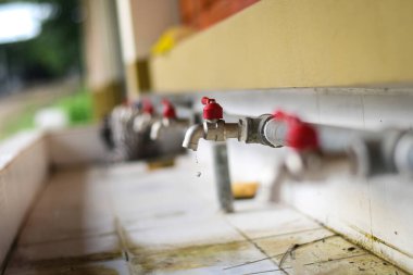 Eski musluktan su damlaları temiz bir damlaya damlıyor çünkü kapanış tamamen kapanmamış. Yaşlı paslı musluk su sızdırıyor.