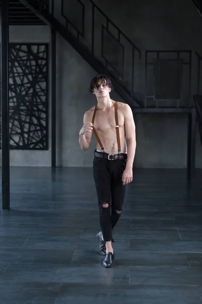 Yakışıklı gömleksiz koyu saçlı erkek modeli yırtık kot pantolon ve karanlık bir odada jartiyer